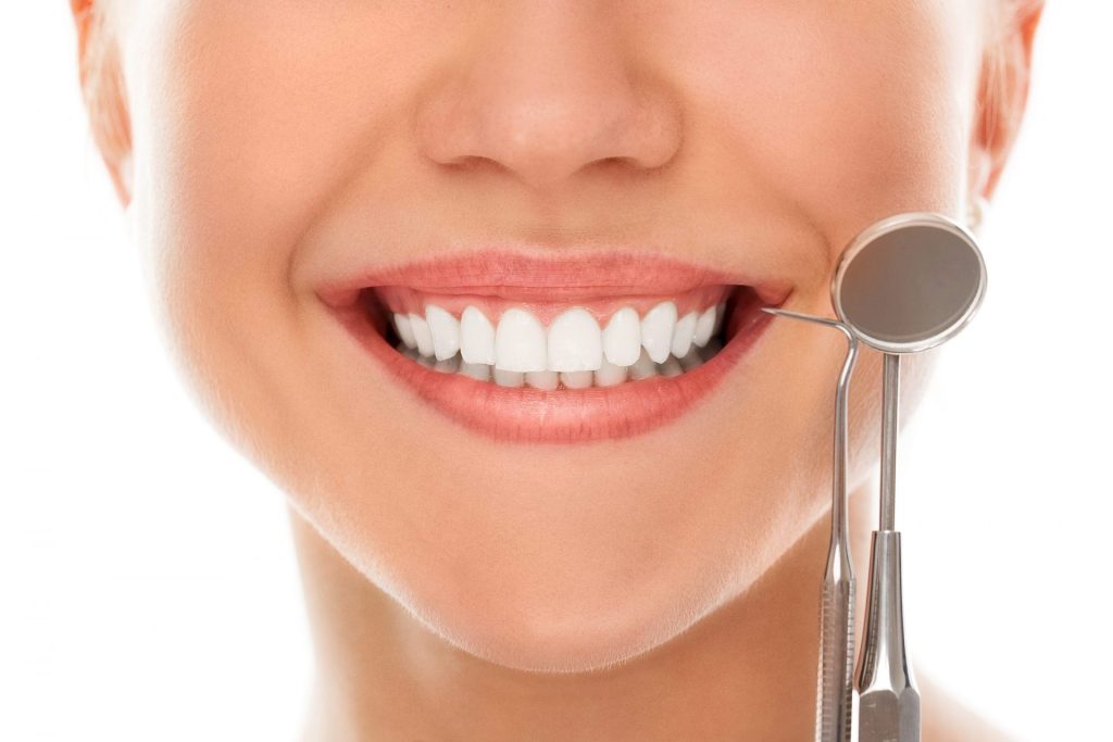 Chica sonriendo al lado de una lupa para dientes